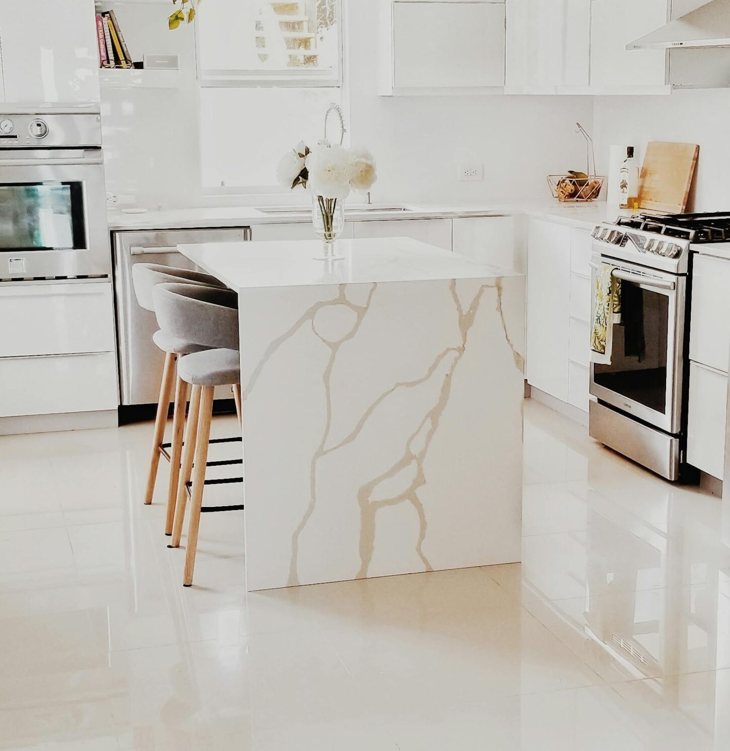 A bright, modern kitchen featuring white cabinetry, stainless steel appliances, and minimalist decor.